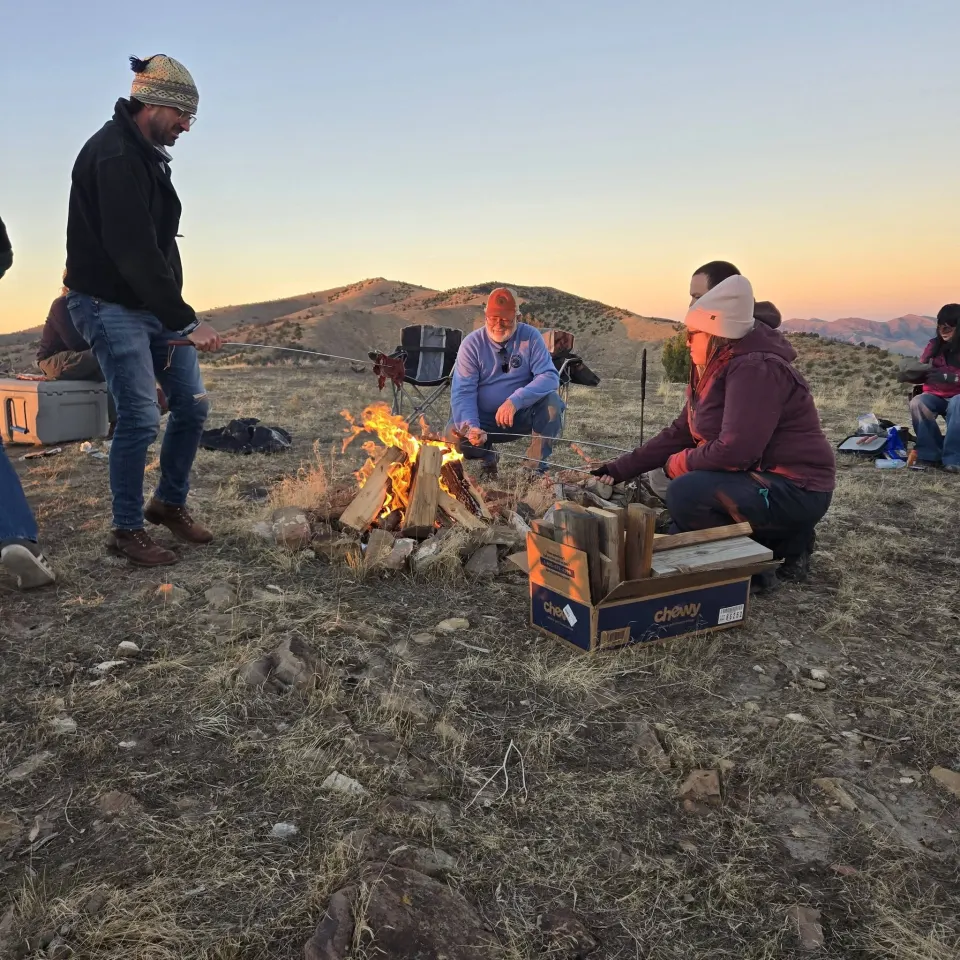 Club members gathered around a campfire at sunset
