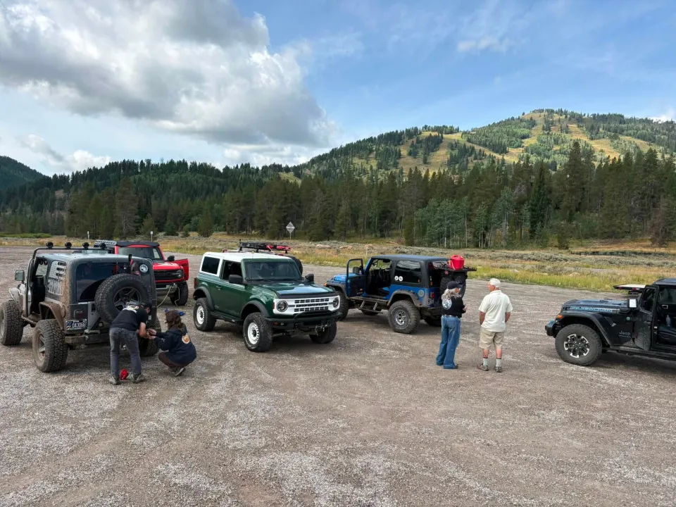 Members talking and preparing their vehicles at a mountain trailhead
